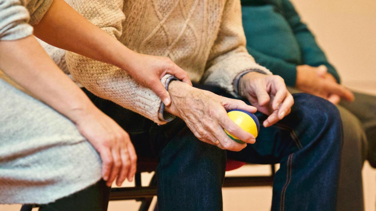 Una persona la mano ad una persona anziana che tiene una palla.